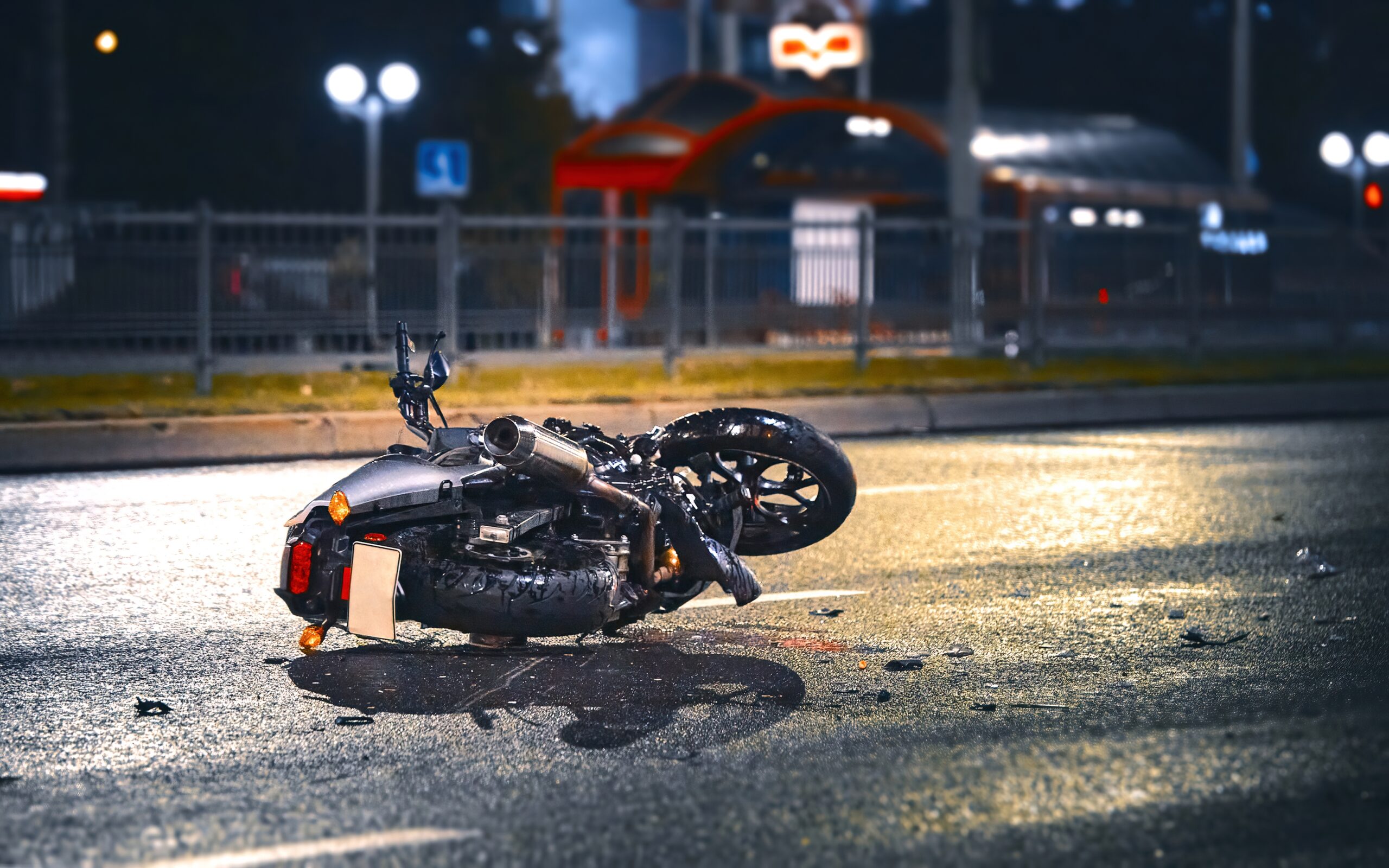 Motorcycle lying on the road after a nighttime crash, representing a motorcycle accident and serious injury risk on city streets Motorcycle lying on the road after a nighttime crash, representing a motorcycle accident and serious injury risk on city streets