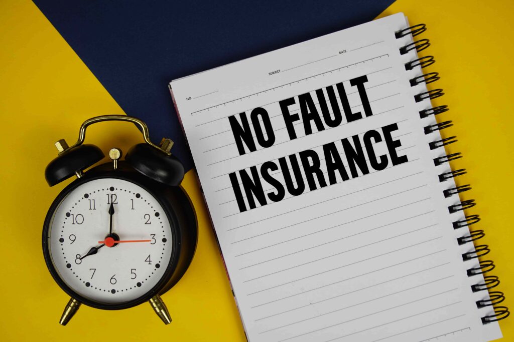 No-fault insurance concept with alarm clock and notebook labeled &lsquo;No Fault Insurance,&rsquo; representing insurance claim timelines and coverage rules.