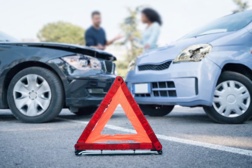 Arlington car accident involving underinsured motorist with warning triangle and blurred individuals in background