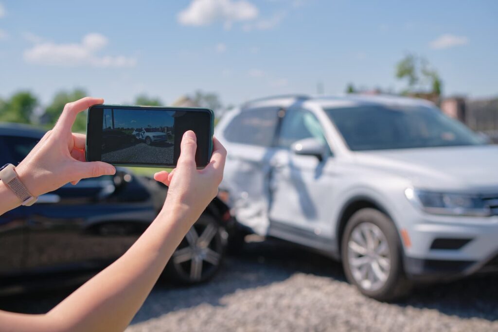 Person taking photos of vehicle damage after a car accident to document evidence for a Dallas car accident claim