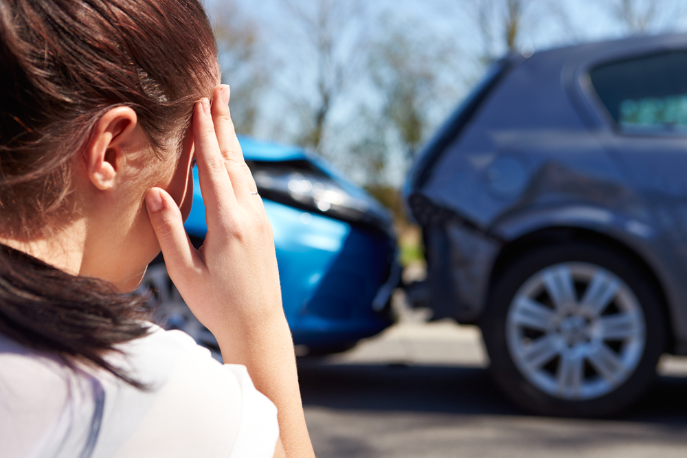 Driver reacting after a rear-end collision involving an out-of-state driver in Texas with damaged vehicles on the road