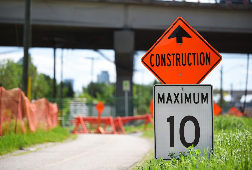 Fort Worth construction zone sign with speed limit warning and roadwork barriers near highway underpass