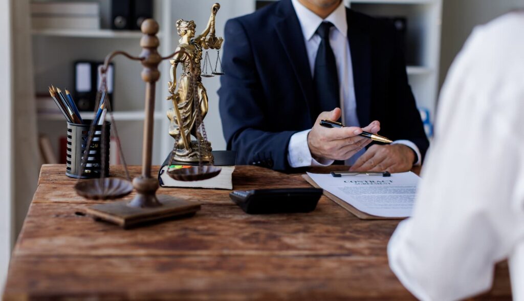 Fort Worth personal injury lawyer reviewing claim documents with client, scales of justice on desk in legal consultation setting