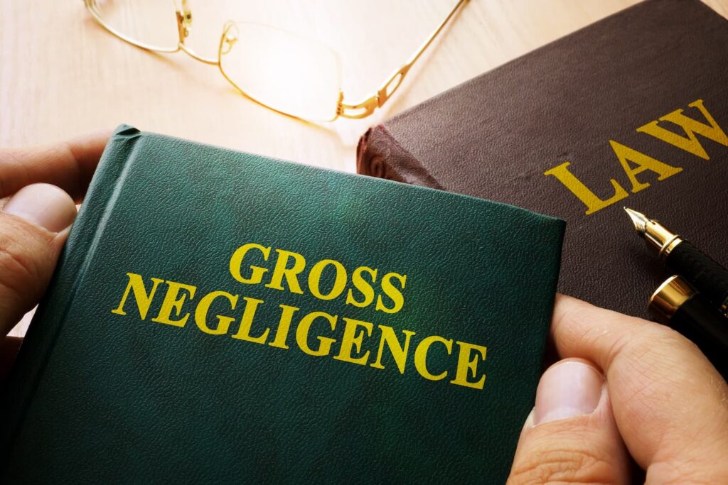 Close-up of a law book labeled gross negligence with pen and glasses, symbolizing legal liability and reckless conduct cases