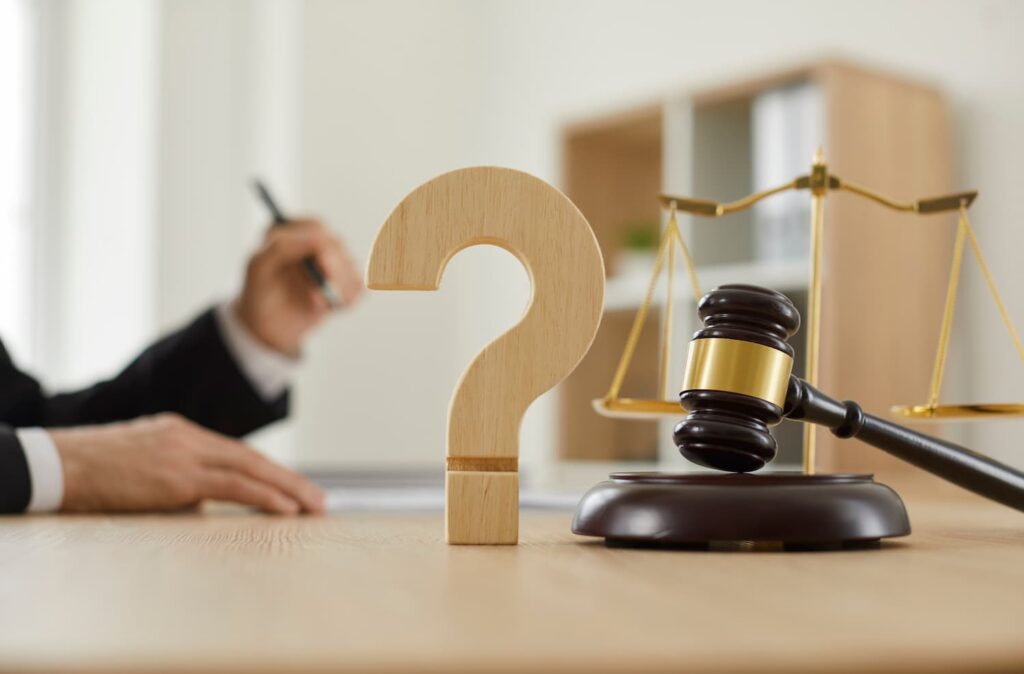 Questions to ask an injury lawyer before hiring concept with judge gavel, legal scales, and question mark symbol on a desk