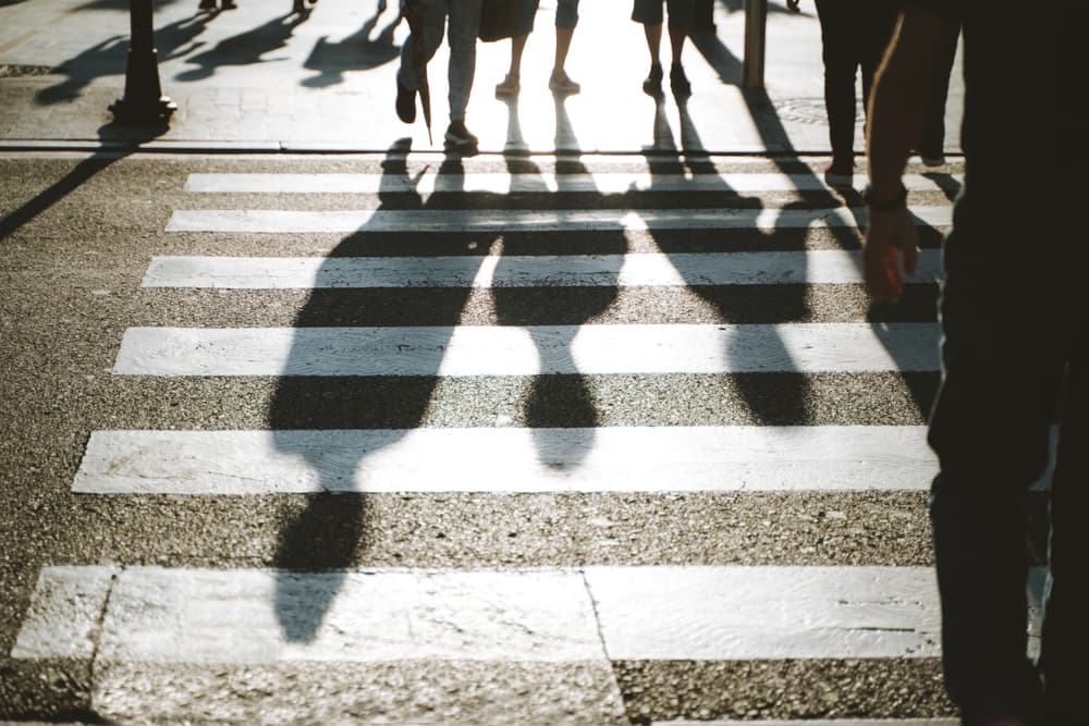 Siluetas de peatones cruzando un paso de peatones a contraluz
