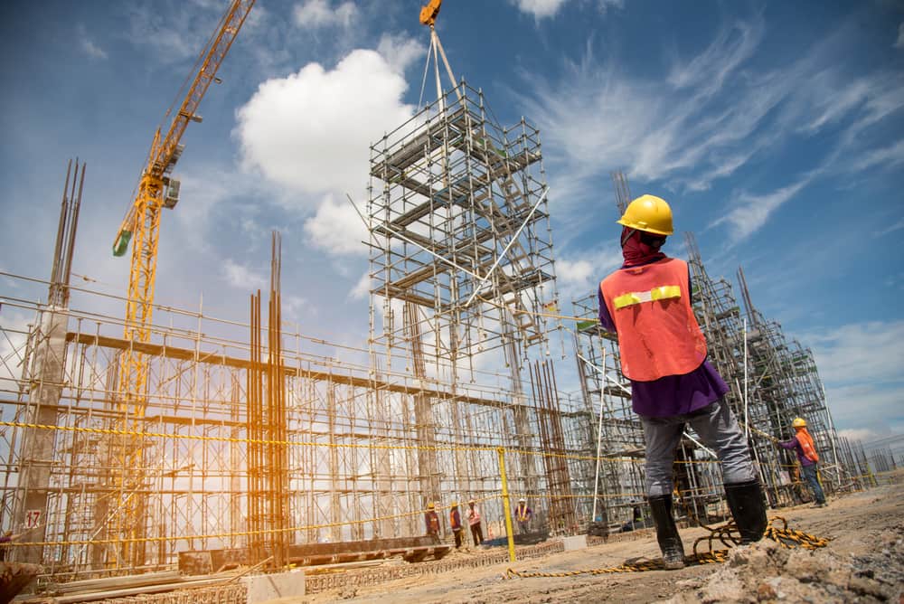 Trabajadores de la construcción que realizan tareas cerca de andamios y una grúa torre en una obra comercial en curso