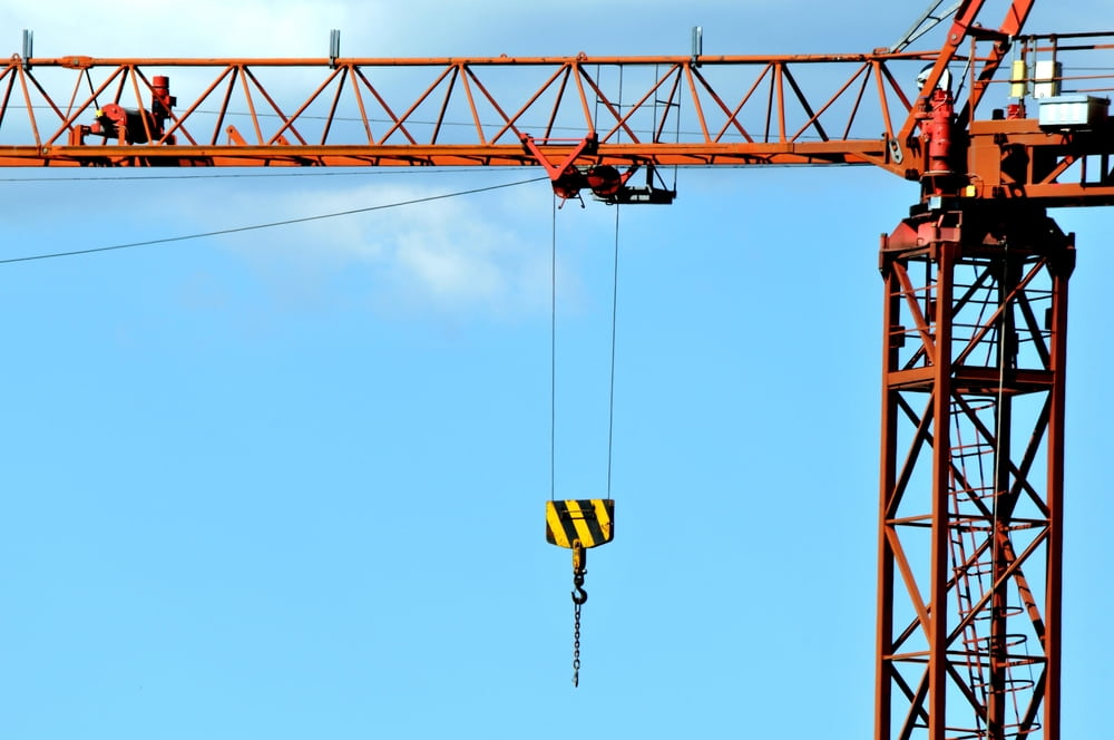 Tower crane with a suspended hook above a construction site