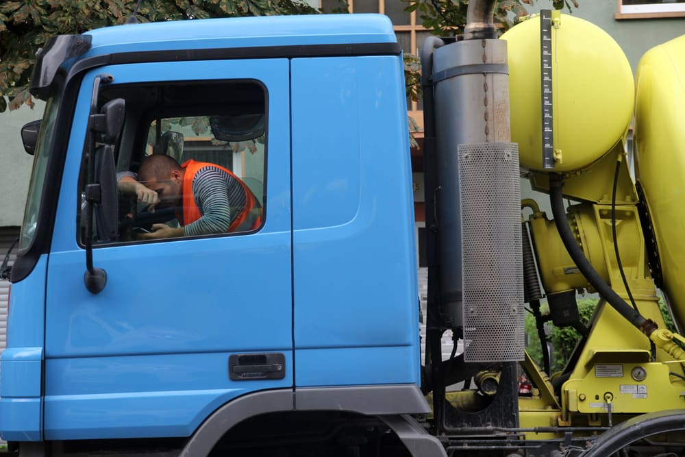 Fatigued truck driver resting his head inside the cab of a commercial truck.